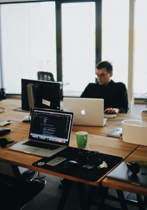 A web developer working on code in a modern office setting with multiple devices.